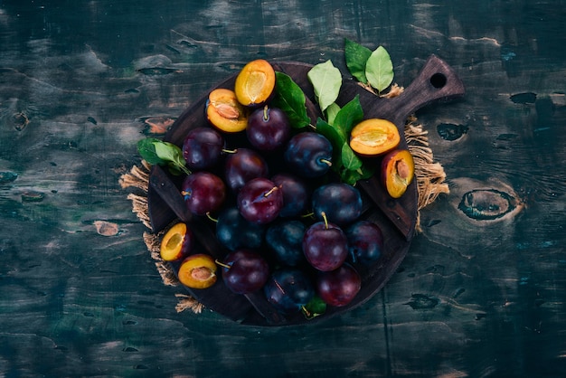 Fresh plums with leaves Fruits On a black wooden background Top view Free space for your text