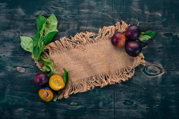 Fresh plums with leaves Fruits On a black wooden background Top view Free space for your text