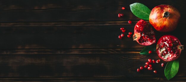 Fresh pomegranate fruits as whole and cut on a rustic wooden table