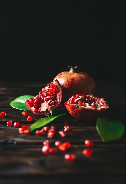 Fresh pomegranate fruits as whole and cut on a rustic wooden table