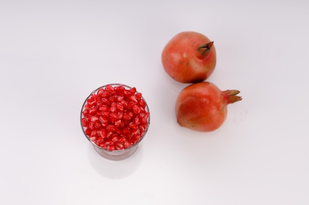 Fresh Pomegranate seed arranged in a glass container with fresh fruit placed beside it