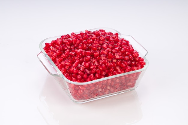 Fresh Pomegranate seed arranged in a square glass container  on white background.