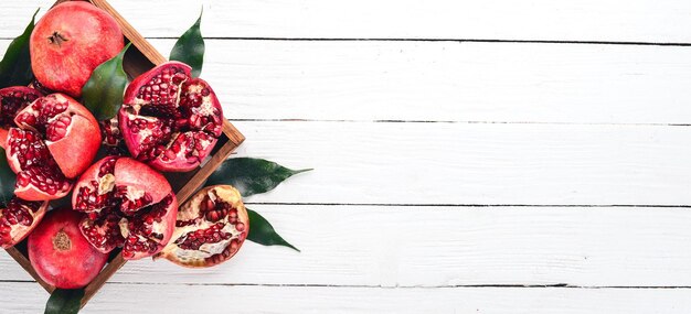 Fresh pomegranate in a wooden box. On a wooden background. Top view. Copy space.