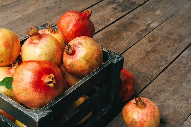 Fresh pomegranates in an old box on wooden background