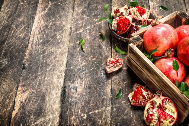 Fresh pomegranates in an old box. On a wooden table.