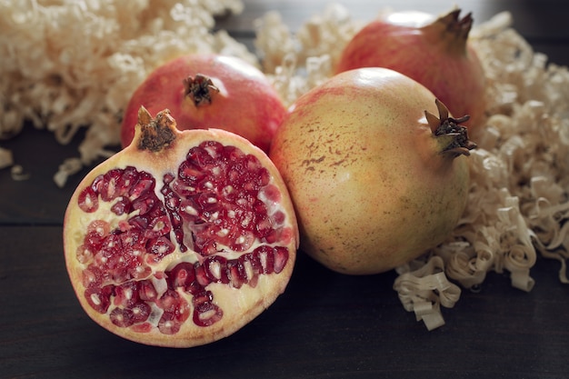 Fresh Pomegranates and sliced pomegranate with seeds on wooden table