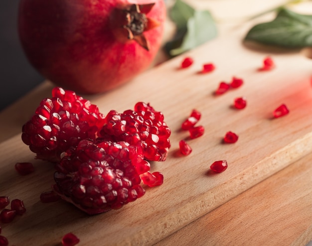 Fresh pomegranates with leaves on wooden background