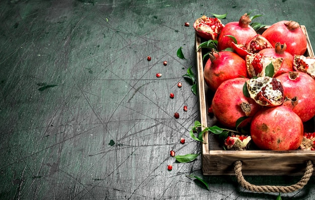 Fresh pomegranates on a wooden tray. On a rustic background.