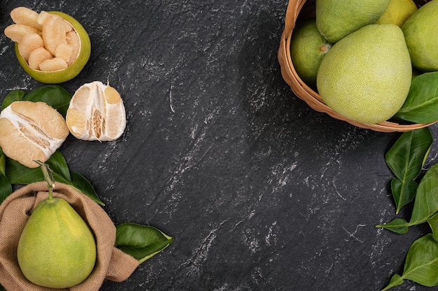 Fresh pomelo grapefruit in bamboo basket with green leaf on dark black slate background Seasonal fruit for MidAutumn Festival Top view Flat lay