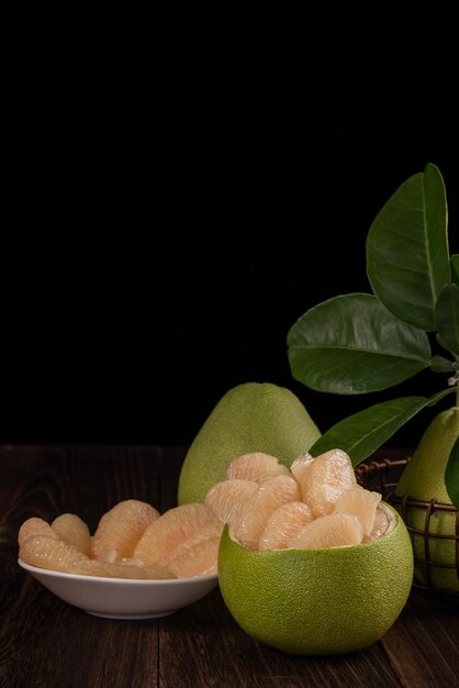 Photo fresh pomelo pummelo grapefruit shaddock on wooden table over black background close up copy space fruit for midautumn festival