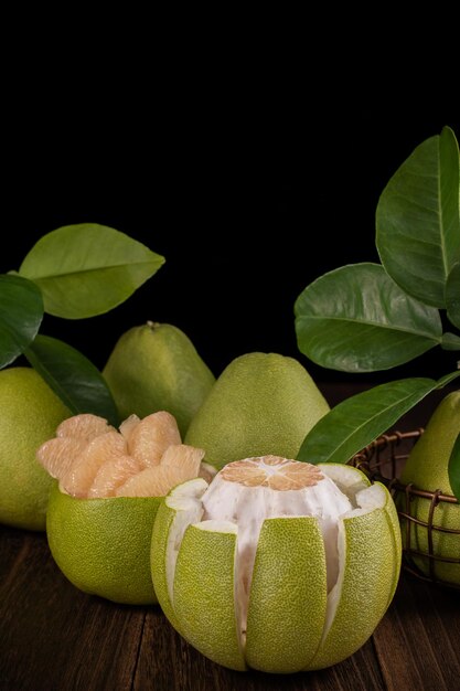 Photo fresh pomelo pummelo grapefruit shaddock on wooden table over black background close up copy space fruit for midautumn festival