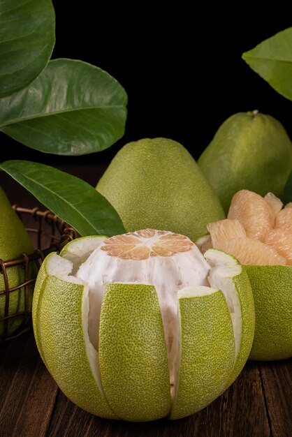 Photo fresh pomelo pummelo grapefruit shaddock on wooden table over black background close up copy space fruit for midautumn festival