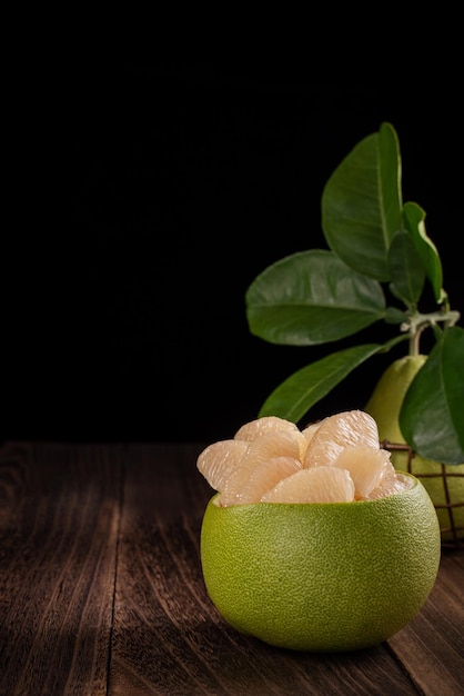 Fresh pomelo pummelo grapefruit shaddock on wooden table over black background close up copy space Fruit for Midautumn festival