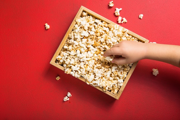Photo fresh popcorn spilled out of the box on red