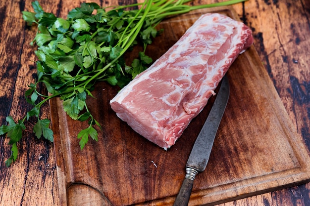 Lonza di maiale fresca su un tagliere usato che riposa su un vecchio tavolo in legno