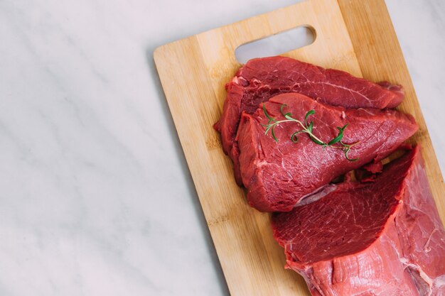 木の板に新鮮な豚肉の生の切り身。まな板の上の赤牛の肉。