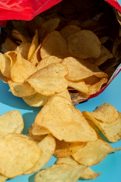 Fresh potato chips in an open package on a blue background.