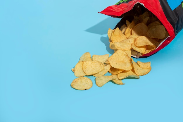 Fresh potato chips in an open package on a blue background.