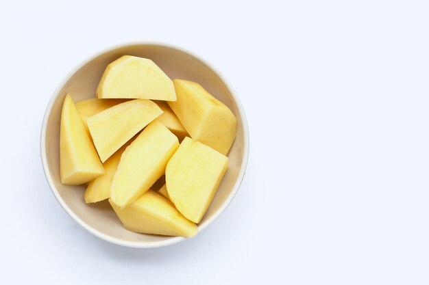 Fresh potato cut into pieces in bowl on white background.