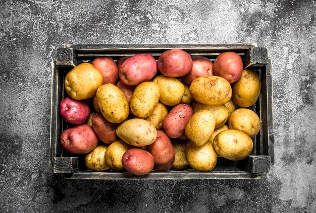 Fresh potatoes in a box on rustic table.