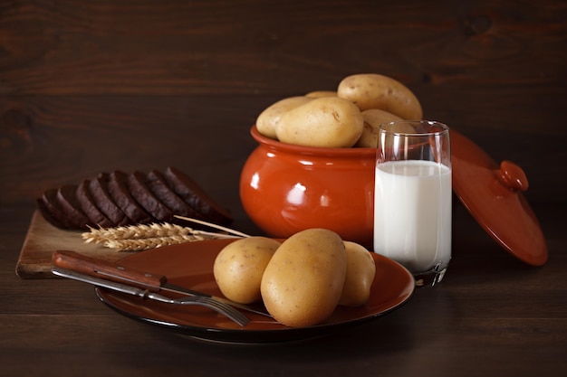 Patate fresche in un piatto di argilla su uno sfondo di superficie in legno scuro.