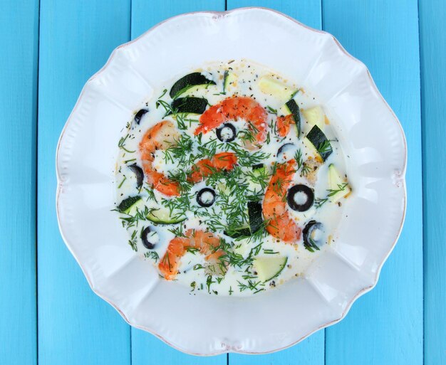 Fresh prawns with olives and avocado in sauce on wooden background