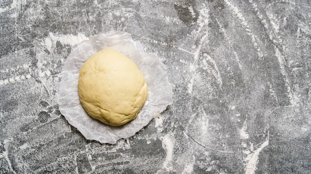 Fresh prepared dough on the paper. On the stone table. Free space for text . Top view