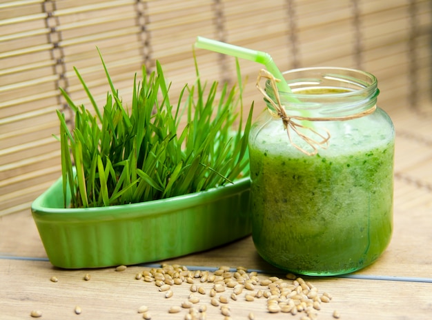 Fresh prepared green frappe juice in glass jar and cereal sprout grass 