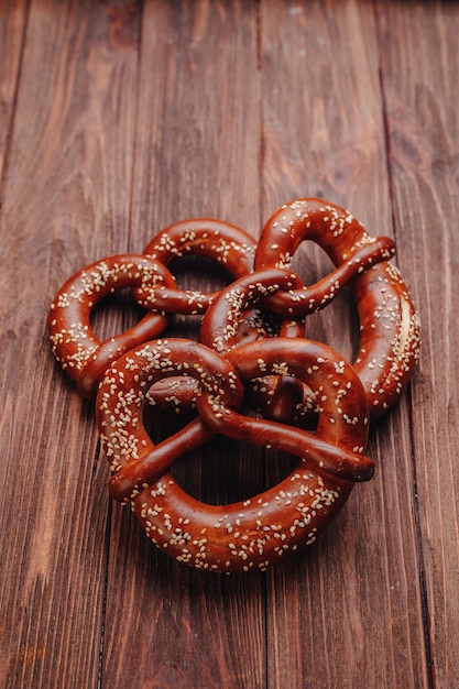 Fresh pretzel sprinkled with sesame seeds on a wooden table