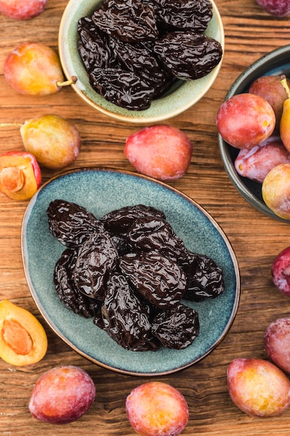 Fresh prune and dried prune on wooden board