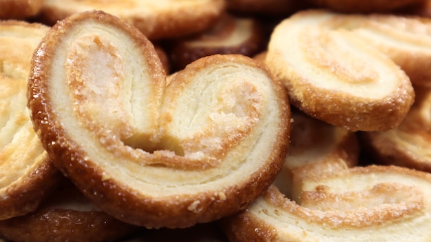 Fresh puff pastry palm cookies in the shape of a heart. Classic French pastries. Pig ear, elephant ear cookies, French hearts. View from above.