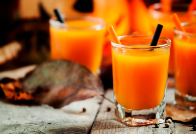 Fresh pumpkin juice on a dark Halloween background with burning candles selective focus