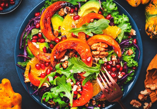 Photo fresh pumpkin salad with lettuce red cabbage avocado arugula pomegranate seeds and nuts healthy vegan vegetarian eating slow comfort food blue table background top view