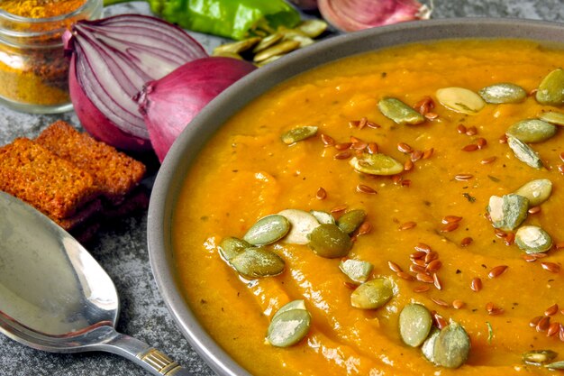 Fresh pumpkin soup in a bowl. Autumn homemade pumpkin soup. Vegan bowl with healthy food.