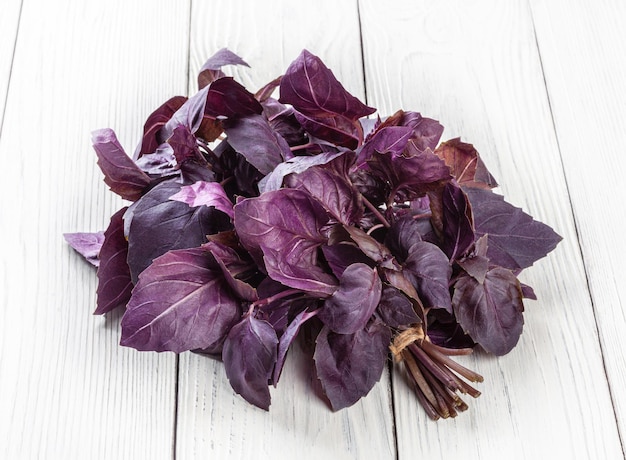 Fresh purple basil leaves on white wooden background