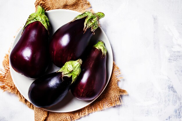 Fresh purple eggplants on plate top view