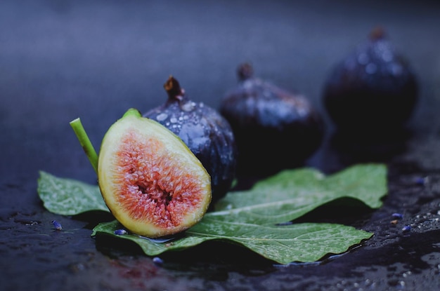 Fresh purple figs lie on the table against dark background. Top view. Flat lay. Food art