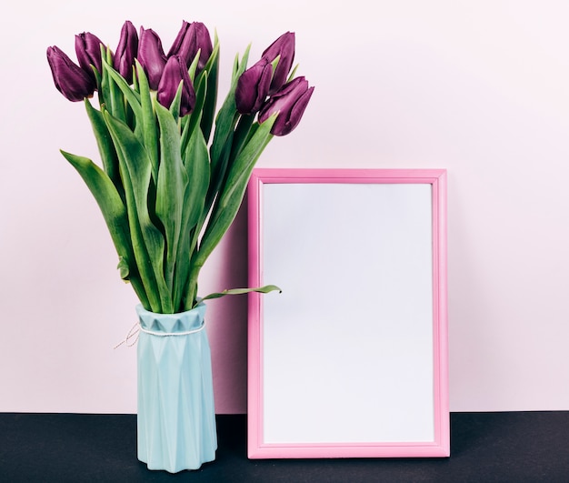 Fresh purple tulip flowers in vase with pink border photo frame
