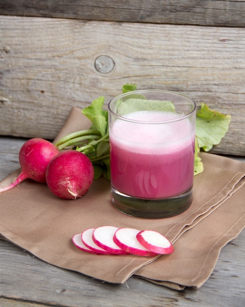 Fresh radish juice in a glass on a wooden table close up