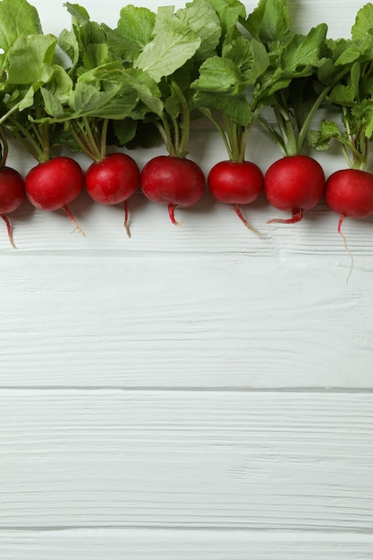 Fresh radish on white wooden surface, space for text