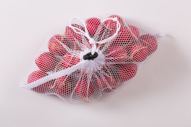 Fresh radishes in reusable packing net isolated on white background