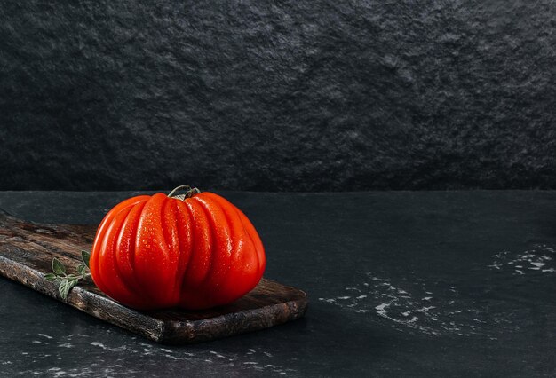 Fresh Raf Coeur De Boeuf tomato on a wooden plank grey background rustic concept stock photo