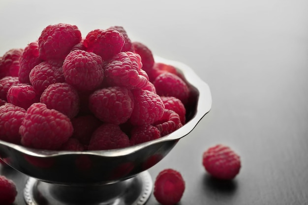 Fresh raspberries in bowl on table closeup