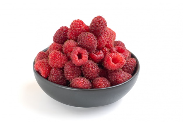 Fresh raspberries in dark bowl isolated on white