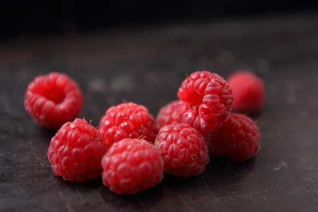 Fresh raspberries fruit on dark background top view. Fresh ripe sweet berries closeup