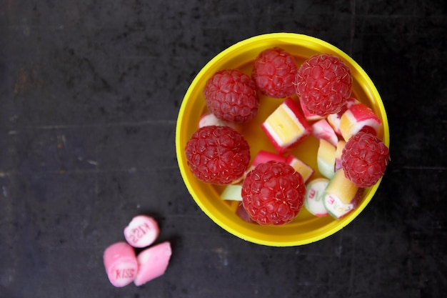 Fresh raspberries fruit and sweet candy on dark background top view Fresh ripe sweet berries closeup