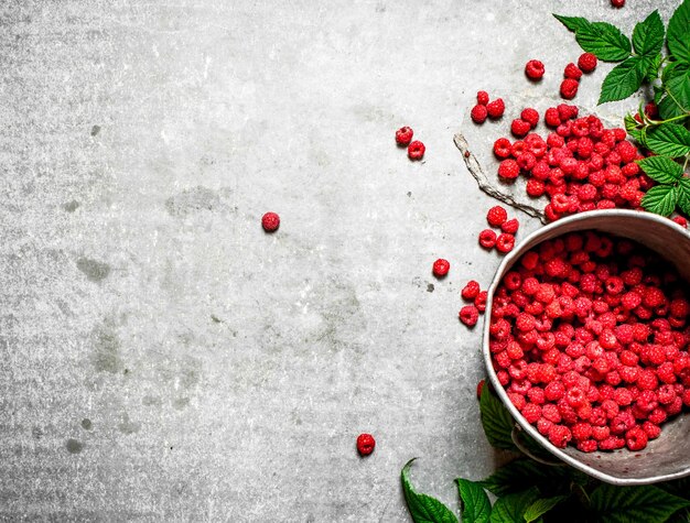 Fresh raspberries in the old pot. On a stone background.