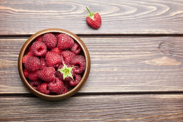 Fresh raspberries in wooden bowl on brown table,top view