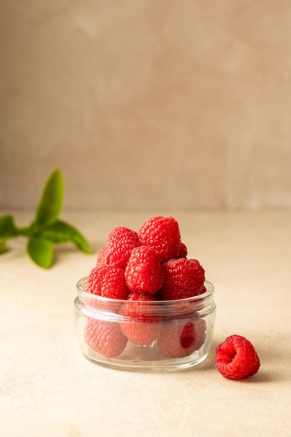 Fresh Raspberry in glass bowl warm neutral background