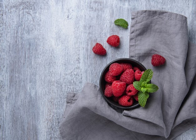 Fresh raspberry with mint in  bowl on old vintage wood background